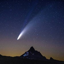 A comet with a bright tail visible against a dark night sky.