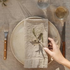 A folded cloth serviette on a formally set dining table