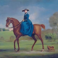 A rider sitting sideways on a horse in a side-saddle