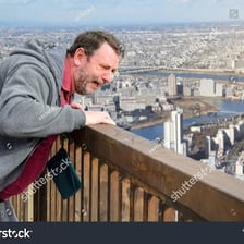 A person viewing a great height from the top of a tall building.