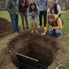 A person placing an object into a burial hole