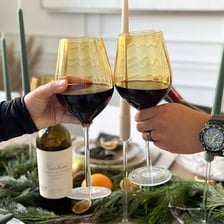 A glass of red wine in a social party setting.