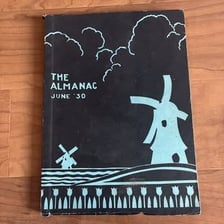 A vintage almanac open beside other reference books