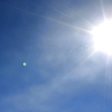 The bright Sun shining in a clear blue sky.