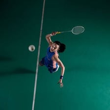 A badminton player striking a shuttlecock on court