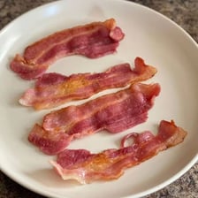 Several cooked bacon rashers arranged on a plate