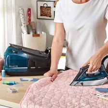 A clothes iron smoothing a piece of fabric.