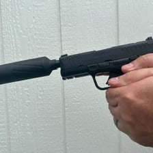 A firearm fitted with a cylindrical suppressor, commonly called a silencer.