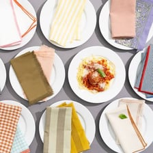 A folded cloth napkin beside tableware on a dining table