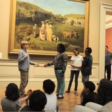 A group of people arranged in a still, theatrical artistic scene.