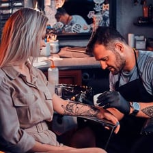 A tattoo artist applying a tattoo to a client