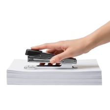 A stapler fastening a small stack of paper sheets.