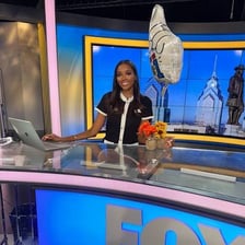 A television presenter speaking in a studio.