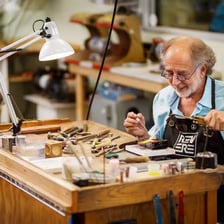 A jeweller working with tools at a jewellery-making bench