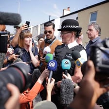 A journalist reporting with a microphone and notebook.