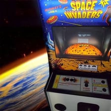 An arcade screen showing the Space Invaders game with rows of descending aliens.