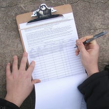 A person signing a petition on a clipboard.