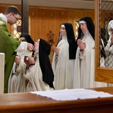 A nun kneeling in prayer inside a church