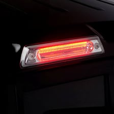 A car viewed from behind with its red brake light illuminated.