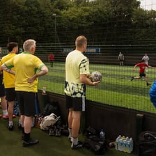People casually kicking a football around in a park