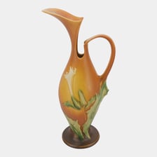 An antique ceramic ewer with a handle and pouring spout.