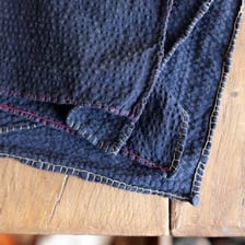 Stitches securing the folded edge of a piece of fabric.