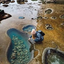 A shallow pool of seawater among coastal rocks at low tide.