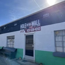 A small, unassuming restaurant identified with the phrase “hole in the wall.”