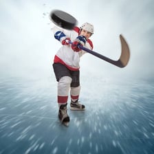 A hockey player shooting the puck toward the goal.