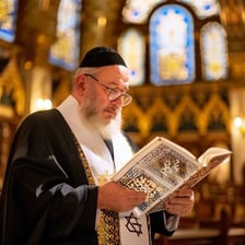 A rabbi reading from the Torah in a synagogue.