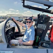 A fighter pilot seated in the cockpit of a military jet.