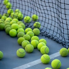 A ball resting on a tennis court near the net.