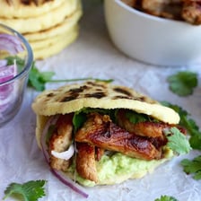 A round cornmeal arepa split open and filled with savory ingredients.