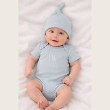 A newborn baby wearing a one-piece cotton garment