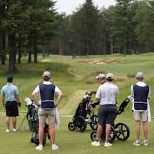 A golf caddie holding a selection of golf clubs