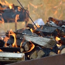 A metal fireplace poker resting beside a burning fire