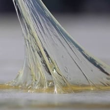 Wet glue forming a sticky strand on a surface