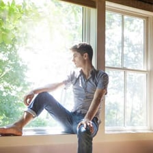 A person sitting and thinking thoughtfully by a window.