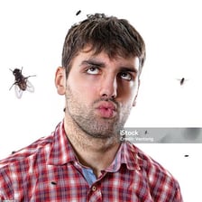 A person reacting with irritation to a buzzing fly.