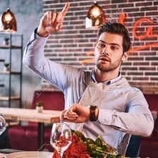 A restaurant diner signaling for the bill.