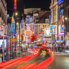 A London West End street lined with theatre signs and marquees.