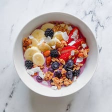 A cereal bowl beside a bowl filled with an acai smoothie mixture and toppings.