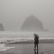 A beach under gray skies during rainfall.
