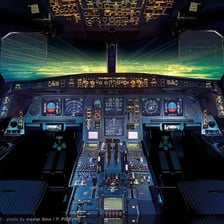 An airplane cockpit autopilot control panel beside a smartphone keyboard.