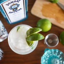 A gin and tonic served with a lime garnish.