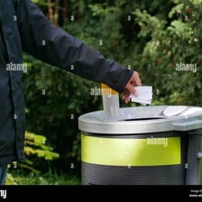 A person throwing an unwanted item into a trash can.