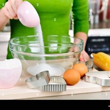 A person adding an ingredient to a bowl.