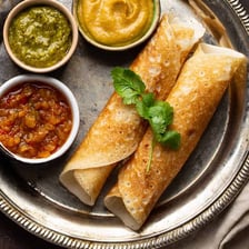 A crisp dosa served on a plate with chutney.