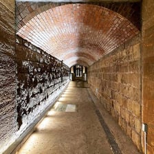 A dark underground sewer tunnel with brick walls
