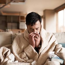 A person resting in bed while feeling ill.